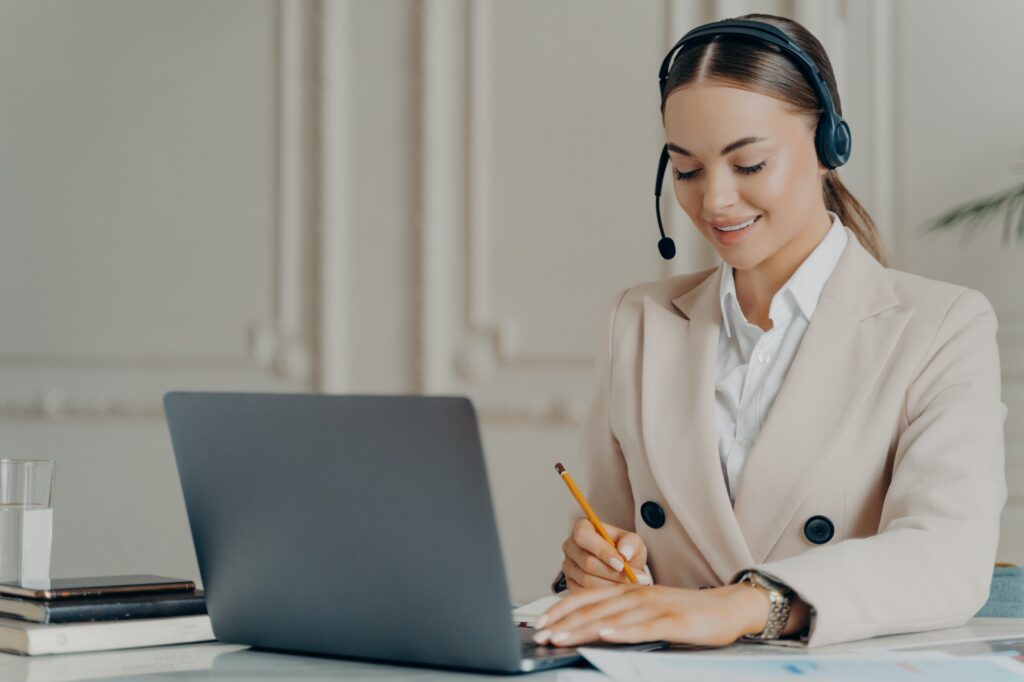 Positive young businesswoman in headset taking part in web conference